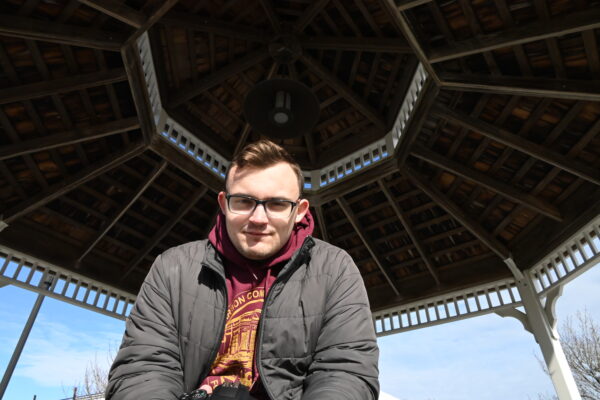 Image shows Brody Owens sitting in a gazebo at main campus.