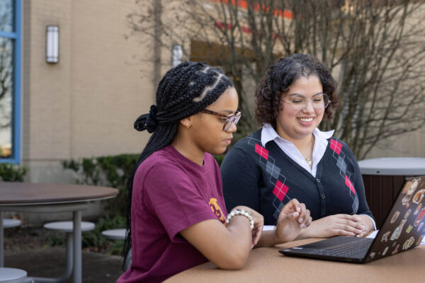 Female students working on laptop outside