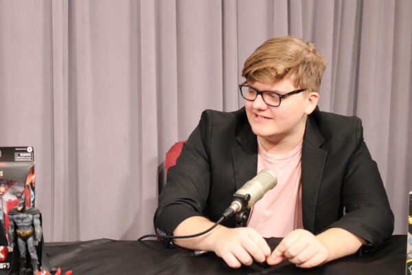 Image shows Konnor Kristiansen sitting at a table with a microphone.