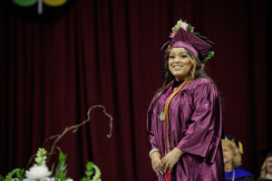 Image shows Margaret Rodriguez Sanchez in graduation regalia standing on the Commencement stage.
