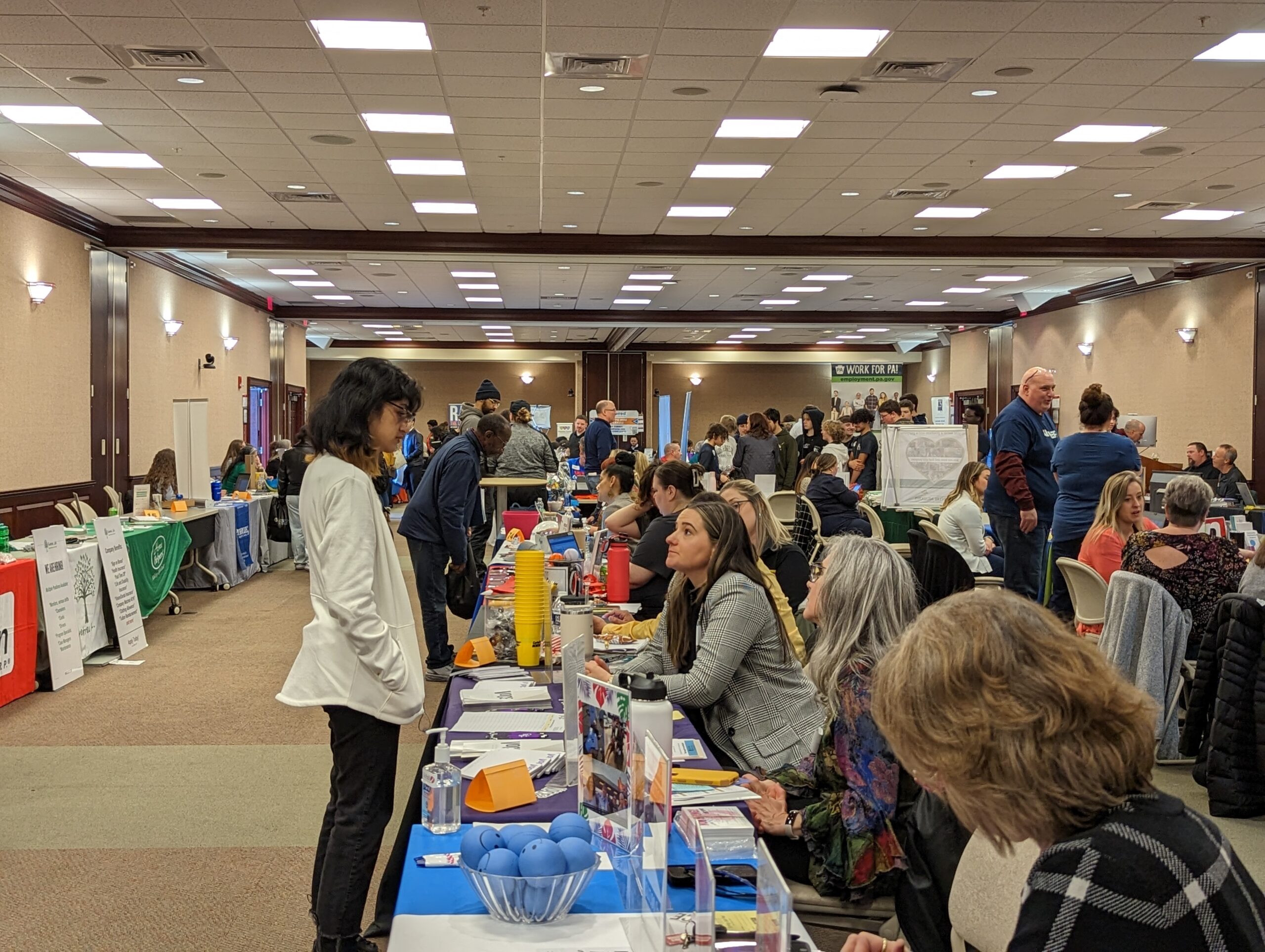 Image shows a student speaking to many employers sitting at tables in the CSC.