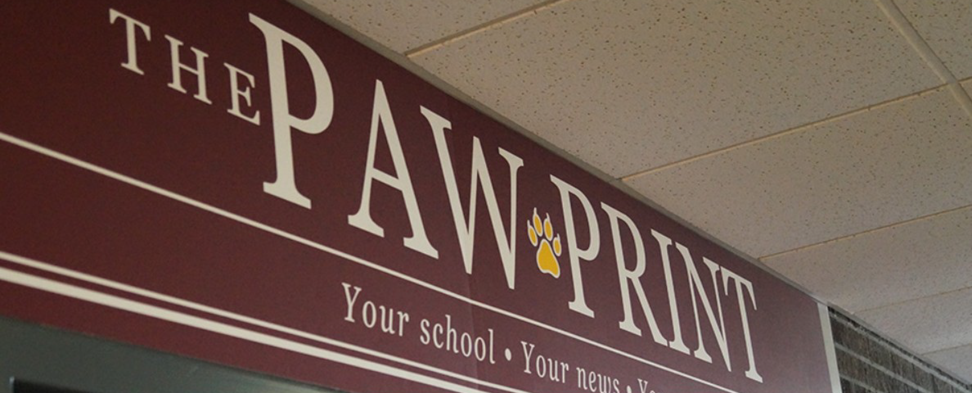 A maroon sign above a doorway reads "The Paw Print" in white lettering.
