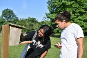 Image shows two students examining a bird box.