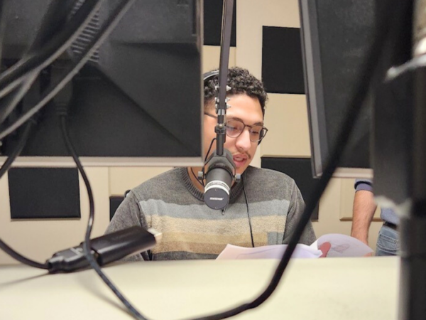 Image shows Alex Ho, LCCC student, speaking into a microphone while conducting a radio show in the WXLV Media Lab.