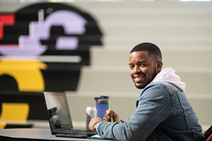 Male student working on laptop in student union